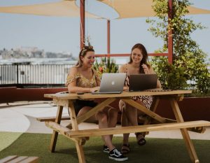 Alieke en Danielle werken op de laptop op het dakterras