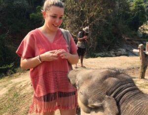 Alieke voert een baby olifant in thaise kleding