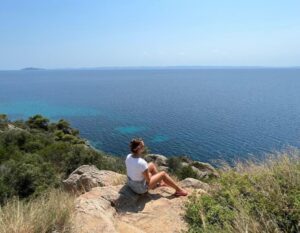 danielle sits by the sea in Greece