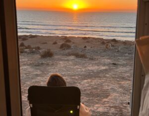 sitting in front of the camper with sunset