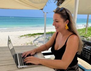 alieke werkt op laptop aan het strand