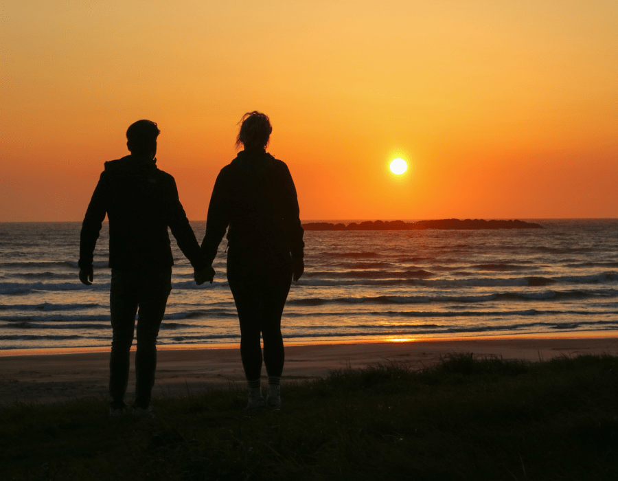 Irene and her boyfriend at sunset on the beach, silhouetted against the sky