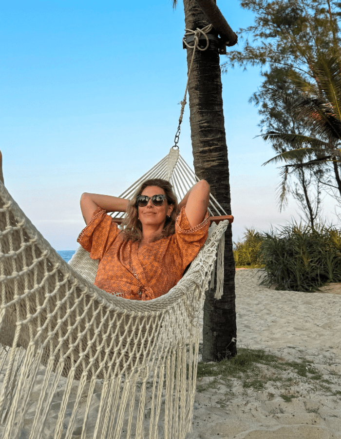 Irene in a hammock hanging from a palm tree on the beach  