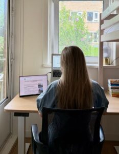 alieke zit te werken aan het sta-zit bureau op 2 schermen