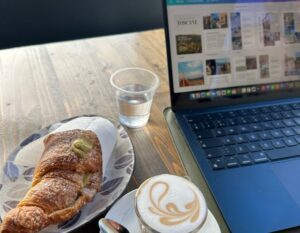 table with a laptop, a pistachio pastry, and coffee in Italy
