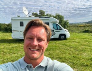 henno met op de achtergrond de camper op een grasveld