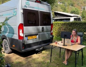alieke werkt op haar laptop naast de camper op de campingplaats