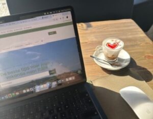 laptop in de zon op een terras met koffie erbij